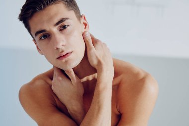 Çıplak adam elleriyle yüzüne dokunur. Güzel görünümlü esmer model.