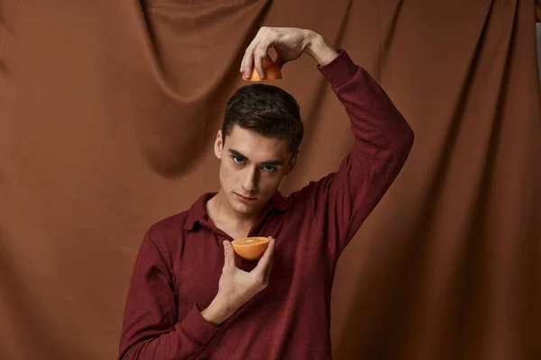 Homem com laranjas nas mãos em tecido modelo de estúdio de fundo — Fotografia de Stock