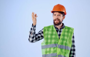 Kasketli duygusal bir mimar ve mavi arka planda elleri ve yansıtıcı merhamet jestleri.