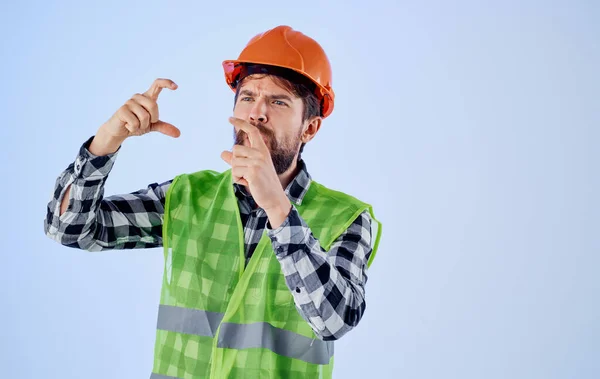 Emotionele architect in harde hoed en reflecterende medelijden gebaren met zijn handen op een blauwe achtergrond — Stockfoto