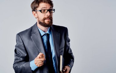 Elinde not defteri olan bir iş adamı gri bir arka plan ve Bitcoin kripto para.