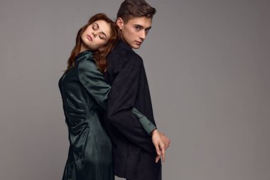 Aşık erkekler ve kadınlar, gri bir arka planda birbirlerine sırtlarını dönerek dururlar.