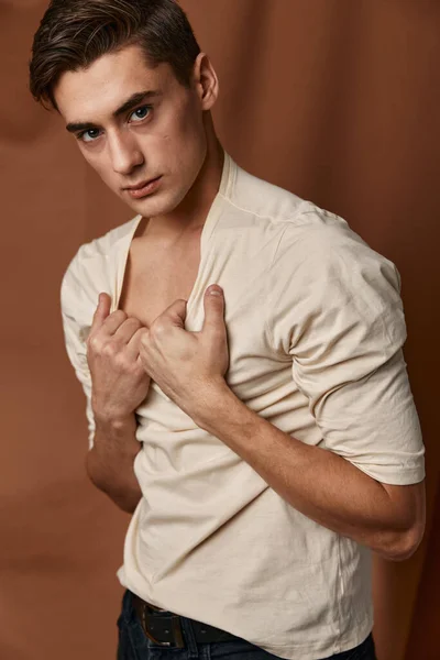 Ένας χαριτωμένος νεαρός κρατά το κολάρο ενός φούτερ μοντέρνο στυλ μόδα casual φθορά — Φωτογραφία Αρχείου