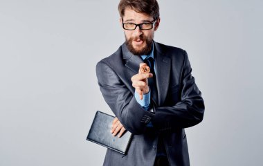 Ellerinde bozuk para ve şaşkın bakışları olan bir iş adamı Bitcoin kripto para ile el kol gezer.
