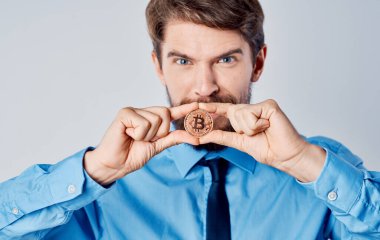 Mavi gömlekli, kravatlı, elinde bozuk para olan bir iş adamı Bitcoin kripto para.