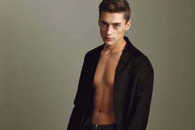 Düğmeleri iliklenmemiş gömlekli bir adam modellere poz veriyor.