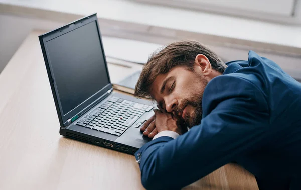 노트북 사무실 앞에 놓여 있는 책상에 양복을 입고 피곤 해 하는 남자 — 스톡 사진