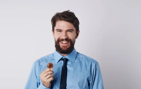 Επιχειρηματίας με ένα νόμισμα και σε ένα μπλε πουκάμισο μια γραβάτα γύρω από το λαιμό του ένα ελαφρύ μοντέλο υποβάθρου — Φωτογραφία Αρχείου