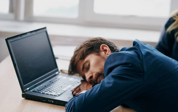 Dizüstü bilgisayarın önündeki çalışma masasında takım elbiseli bir adam yoruldu. — Stok fotoğraf