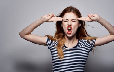 Beyaz tişörtlü güzel bir kadın. Duyguları el hareketleriyle ve stüdyo cazibesiyle ifade ediyor.