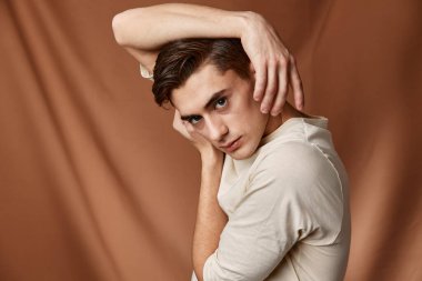 Yakışıklı beyaz ceketli. Eller kafanın üstünde. Yakından poz veriyor.