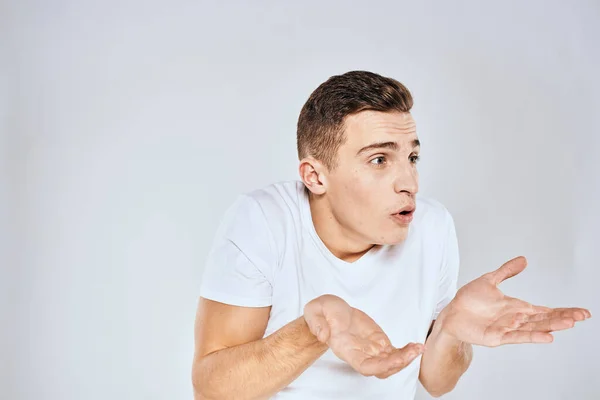 Nice man in a white t-shirt gestures with his hands emotions surprise studio — Stock Photo, Image