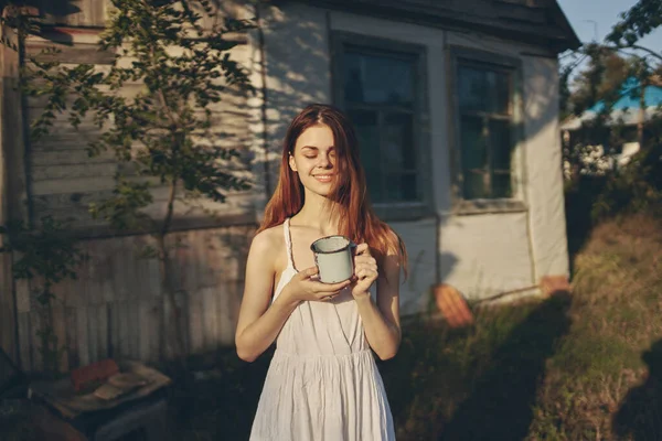 Mujer feliz cerca del edificio con taza de hierro al aire libre en el jardín —  Fotos de Stock