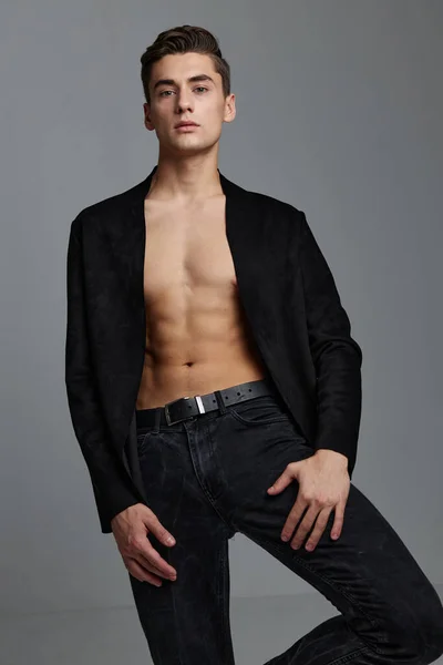 A sexy man in a buttoned jacket with a naked torso holds his hand near his leg — Stock Photo, Image