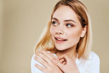 Güzel kadın beyaz tişörtlü eğlenceli duygular bej arka plan kırpılmış görünüm