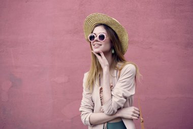 Güneş gözlüklü güzel bir kadın Pembe duvarda yürür