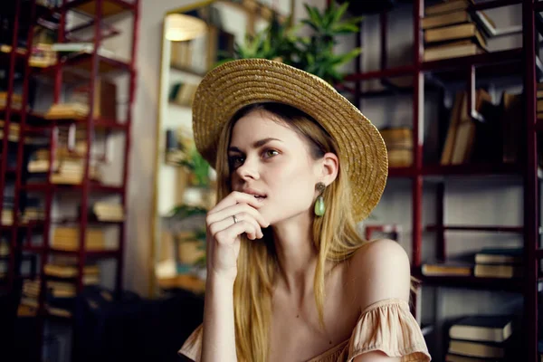 Красива жінка в капелюсі сидить за столом з книгами на задньому плані крупним планом — стокове фото