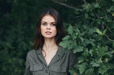 Ormandaki kadın çalıların arkasındaki yeşil yaprakların yanında çekici bir bakış. 