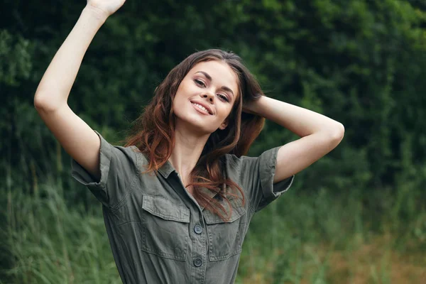 Woman in the forest smile with hands raised up green suit travel vacation summer — Stock Photo, Image