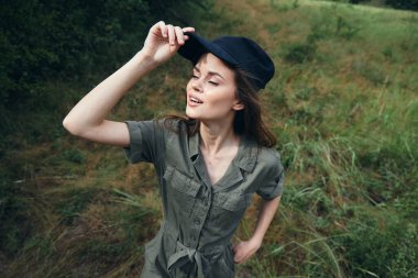 Açık havada, gözleri kapalı, temiz hava alan yeşil yaprakların tadını çıkaran bir kadın. 