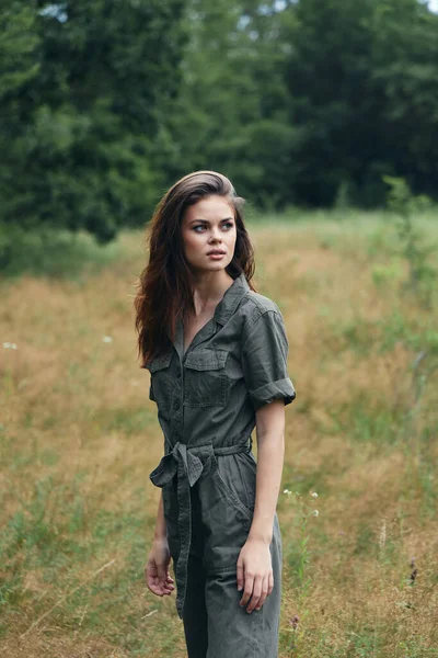 Mujer en el bosque en overoles mira a un lado en el prado —  Fotos de Stock