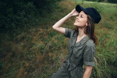 Ormandaki kadın yeşil tulumlu, siyah şapkalı, seyahat eden bir gülümseme ağacı. 