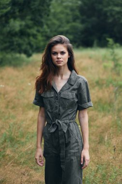 Ormandaki çayırda yeşil tulumlu bir kadın. 