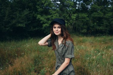 Ormandaki kadın gülümseyen yeşil tulum, yeşil yaprakların arkasında ileriye bakıyor. 