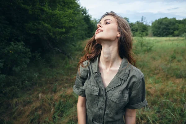 Vrouw op de natuur in groene jumpsuit op zoek naar landschap groene bladeren — Stockfoto