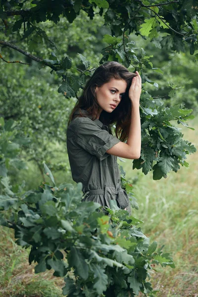 Kvinna i skogen håller hår grön kostym frisk luft bakgrund — Stockfoto