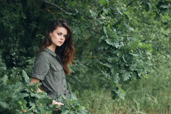 Nő az erdőben tartja a kezét a zsebében zöld levelek háttér — Stock Fotó