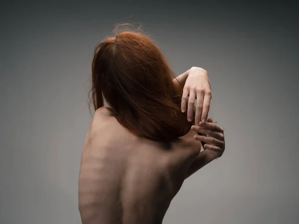 Una sottile donna dai capelli rossi si tocca con le mani dietro la schiena — Foto Stock