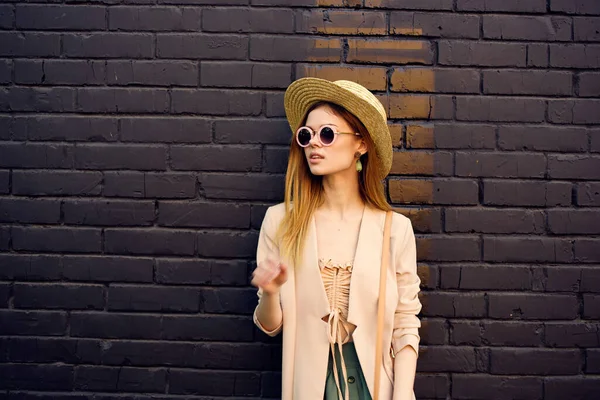 Mujer en gafas de sol y sombrero de decoración pasear al aire libre pared de ladrillo en el fondo — Foto de Stock