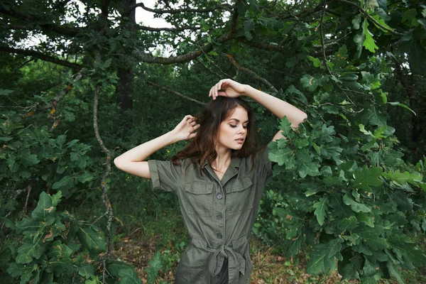 Mujer en el bosque Un árbol mira a un lado de la mano por encima de la cabeza viaje de fondo —  Fotos de Stock