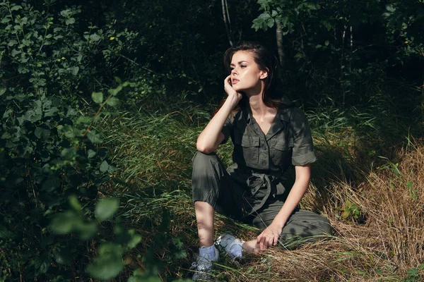 Mulher sentada na grama no fundo da natureza da floresta — Fotografia de Stock