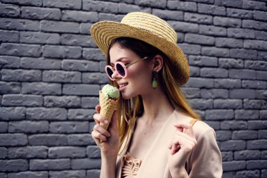 Güneş gözlüğü takan ve şapka takan kadın şehir tarzı tuğla duvar.