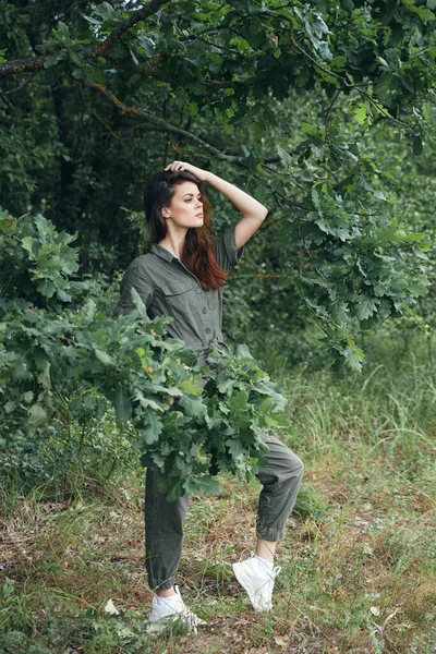 Vrouw in het bos groen bladeren jumpsuit zijaanzicht — Stockfoto