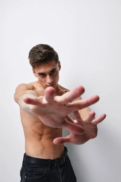 Un hombre con un torso desnudo gestos con las manos delante de su cara contra un fondo claro recortado vista —  Fotos de Stock