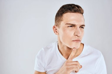 Beyaz tişörtlü duygusal bir adam elini arka planda tutuyor.