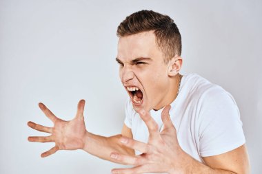 Duygusal adam elleri ile jestler hoşnutsuz beyaz tişört ışıklı arka plan