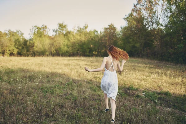 Feliz viagem em um vestido de verão branco correndo na grama na natureza — Fotografia de Stock