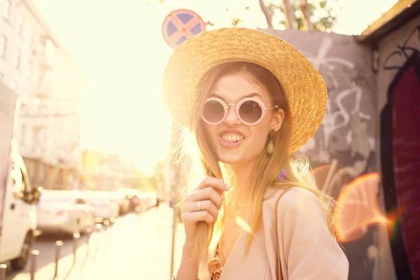 Glada kvinna i hatt och solglasögon går genom staden utomhus i solen — Stockfoto