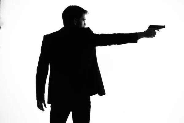 Shadow of a man with a gun in his hands aiming detective crime light background — Stock Photo, Image