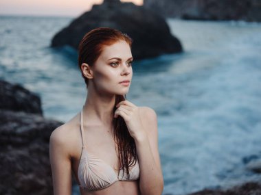 Deniz kenarındaki plajda mayo giymiş seksi bir kadın. Doğanın el hareketleriyle.