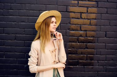 Şehir duvarında güneş gözlüğü takan şapkalı güzel bir kadın.