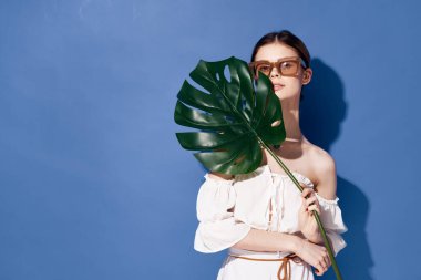 Güneş gözlüğü takan bir kadın yaz gezisi için mavi arka plan