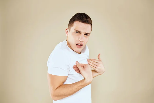 Homme émotionnel expression faciale geste avec les mains blanc t-shirt fond beige — Photo