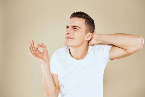 Emotional man facial expression gesture with hands white t-shirt beige background — Stock Photo, Image