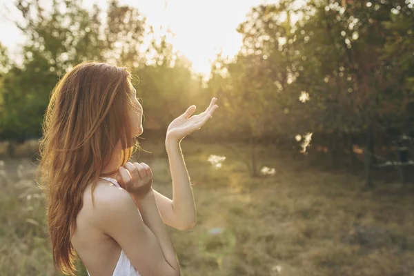 白いドレスを着た魅力的な女性が日没時に自然の中で休んでいます — ストック写真