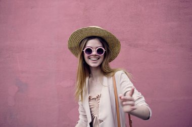 Şehre yürüyen şapkalı duygusal bir kadın pembe duvar arkasında açık hava.